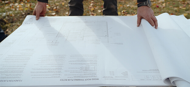 Contractor reviewing detailed foundation and site plans for a residential construction project in Ann Arbor near the University of Michigan.
