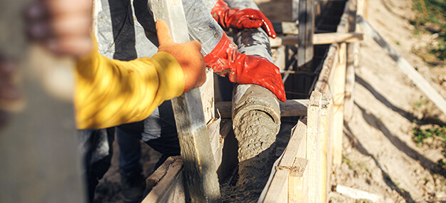 Concrete foundation pouring into formwork during agricultural construction project