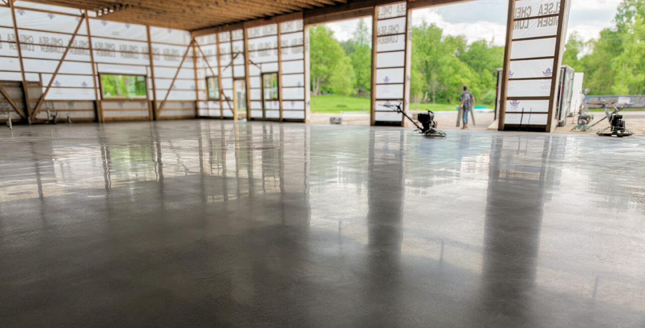 Freshly finished concrete flatwork inside a large shop building with smooth polished surface and open framing