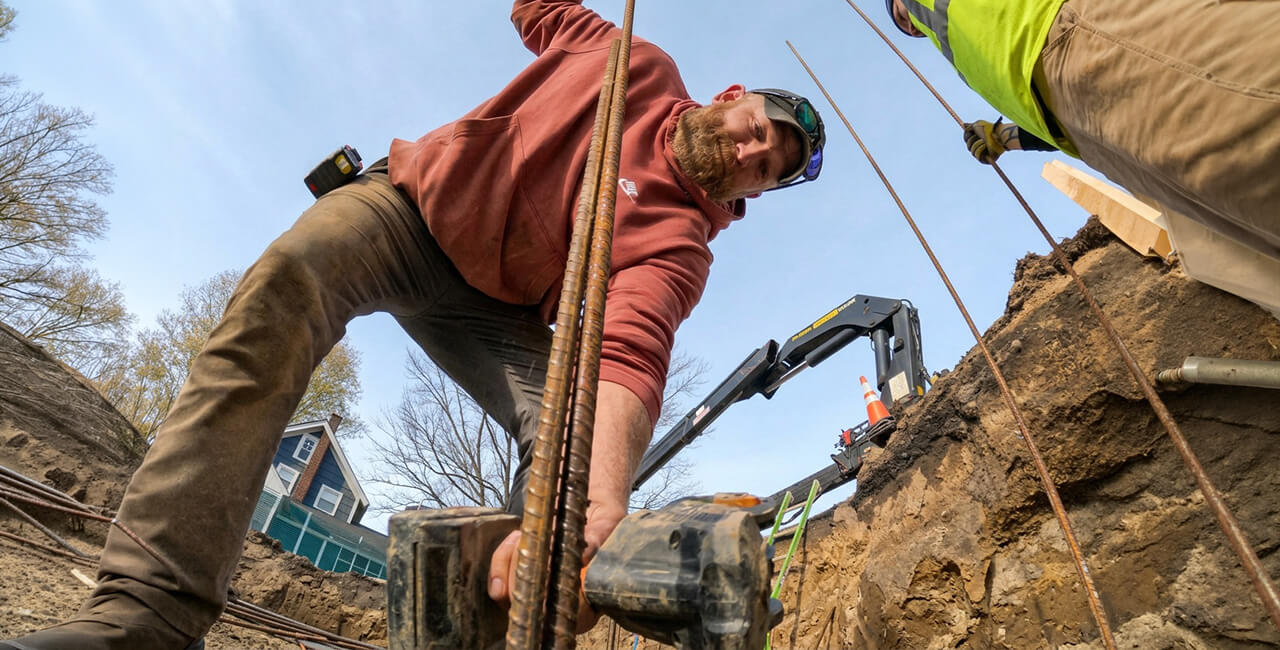 Worker installing rebar for concrete foundation footing on residential construction site in Michigan