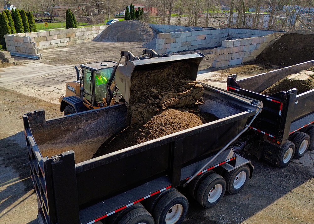 Wheel loader loading soil into dump truck for material hauling by Cutting Edge Construction in Southeast Michigan