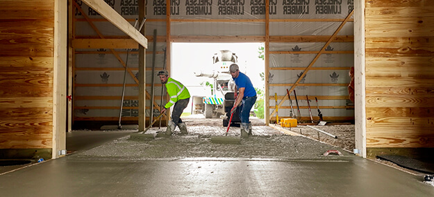 Concrete floor installation inside equestrian barn during construction process