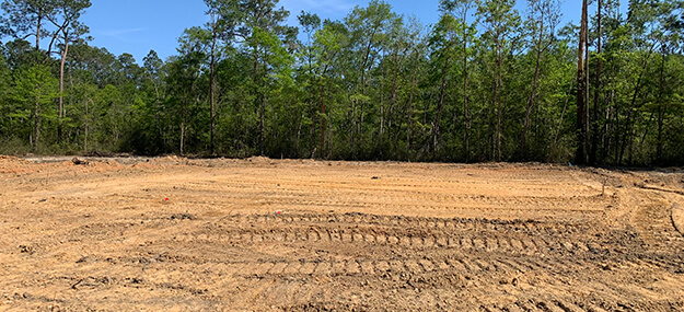 Cleared and graded land ready for construction with trees removed and level dirt surface