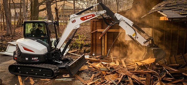 Mini excavator tearing down a residential garage during a demolition project in Ann Arbor, Michigan.